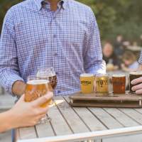 Three people enjoy a flight of beers from Ethereal Brewing.