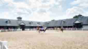 Four horseback riders canter in a circle inside a fenced off field at Kentucky Horse Park.