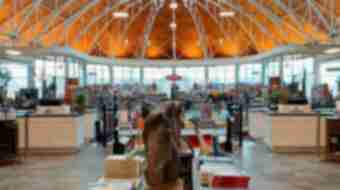 Interior of a large book store filled with bookcases. The entrance of the room has a horse head statue on a table.