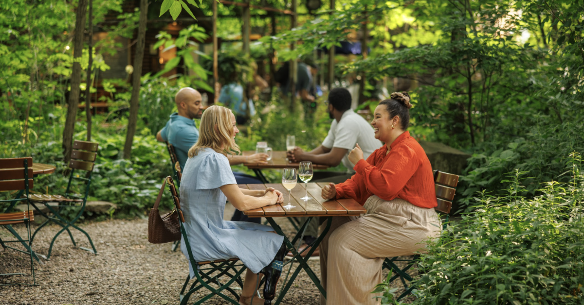 Two individuals drinking wine at a garden cafe